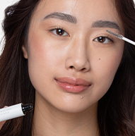 En kvinde fokuserer på at påføre makeup med en børste og fremhæver hendes kunstneriske og personlige plejeproces.